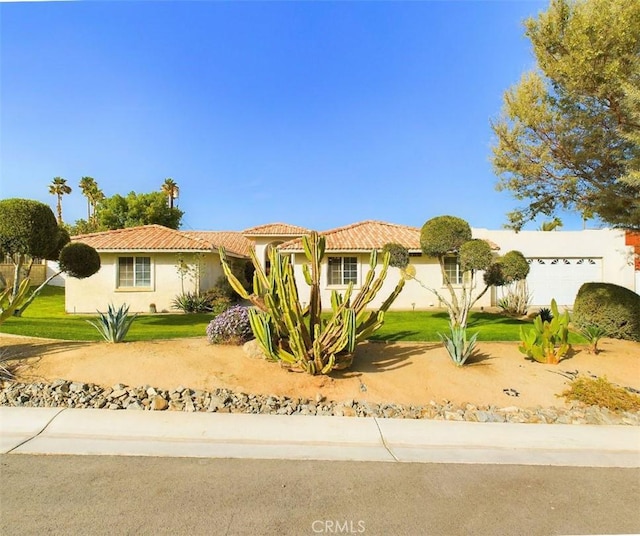 view of front of house with a garage, a front lawn, a tile roof, and stucco siding