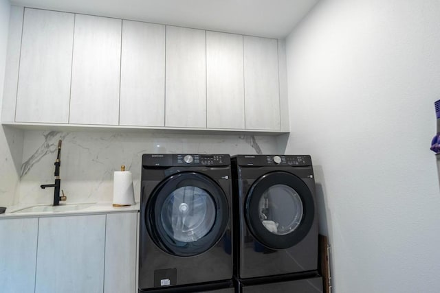 clothes washing area with sink, cabinets, and washing machine and clothes dryer