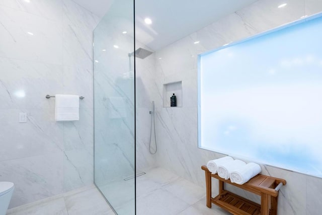 bathroom with tiled shower, tile walls, and toilet