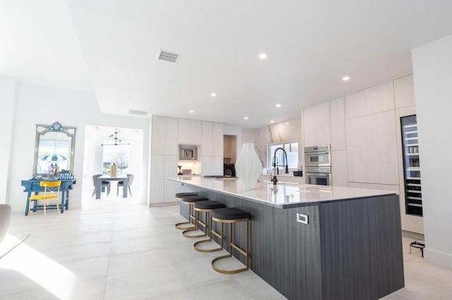 kitchen with white cabinetry, a large island, stainless steel double oven, and a kitchen bar