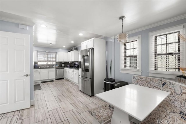 kitchen with hanging light fixtures, white cabinetry, appliances with stainless steel finishes, and a breakfast bar area