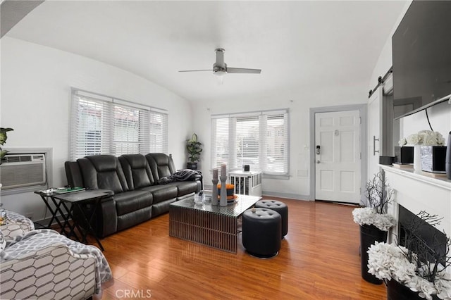 living room featuring hardwood / wood-style floors, an AC wall unit, a barn door, and ceiling fan