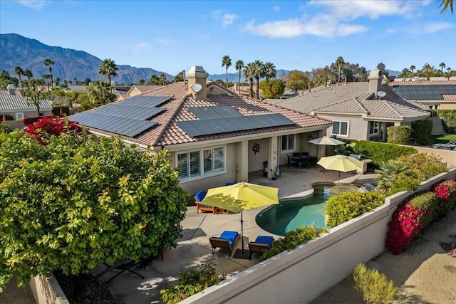 back of house with a mountain view, a patio, and solar panels