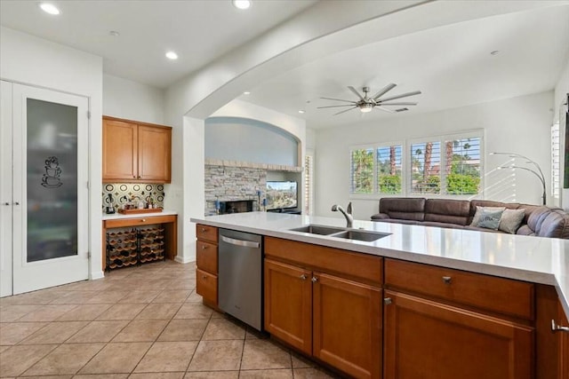 kitchen with sink, light tile patterned floors, dishwasher, ceiling fan, and decorative backsplash