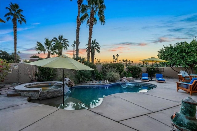 pool at dusk with an in ground hot tub, pool water feature, and a patio