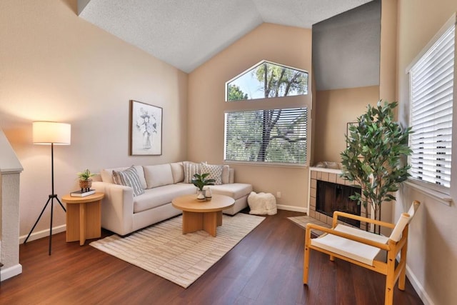 living room featuring a tile fireplace, lofted ceiling, dark wood-type flooring, and a textured ceiling