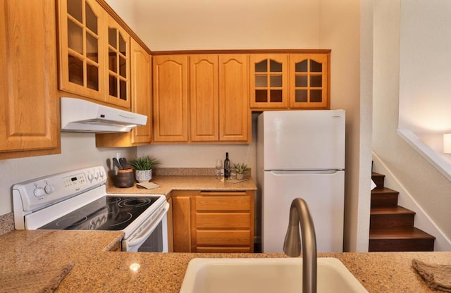 kitchen with light stone counters, sink, and white appliances