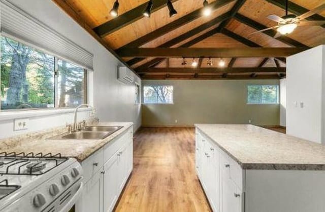 kitchen with sink, white cabinetry, lofted ceiling with beams, wooden ceiling, and light wood-type flooring