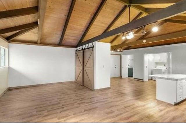 unfurnished living room with lofted ceiling with beams, a barn door, light wood-type flooring, and wood ceiling