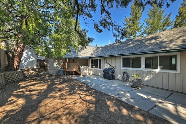 rear view of property featuring a storage unit and a patio