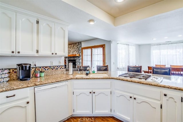 kitchen featuring sink, white appliances, white cabinetry, light stone countertops, and kitchen peninsula