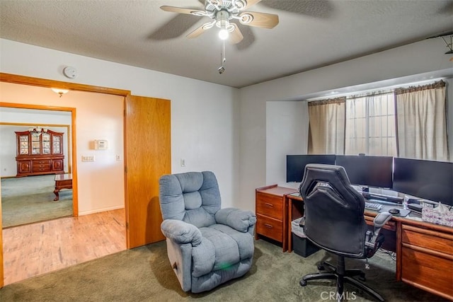 carpeted office featuring ceiling fan and a textured ceiling