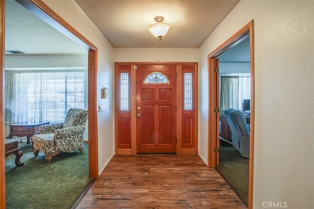 entryway with dark wood-type flooring and a textured ceiling