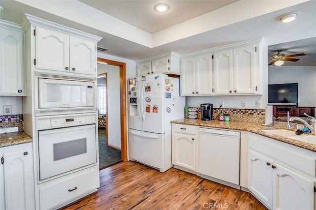 kitchen with sink, white appliances, light hardwood / wood-style flooring, white cabinetry, and light stone countertops