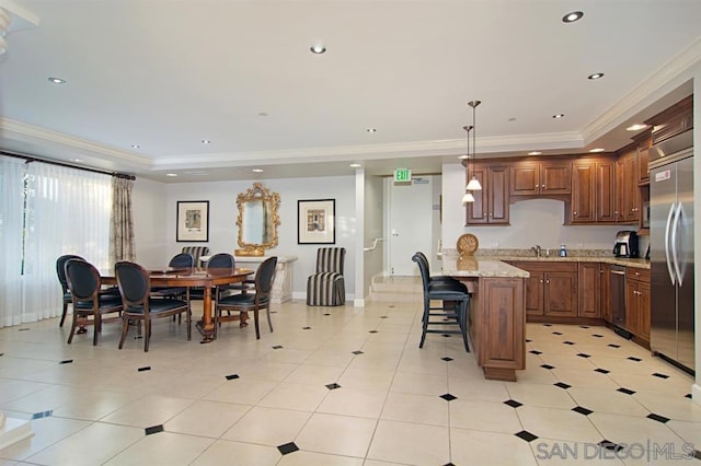 kitchen with crown molding, hanging light fixtures, a tray ceiling, stainless steel appliances, and light stone countertops