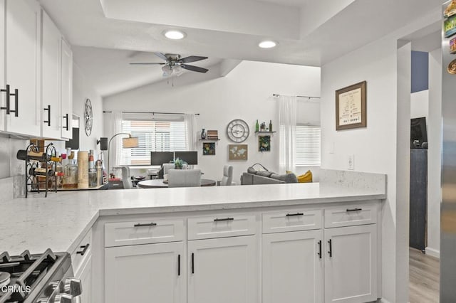 kitchen featuring lofted ceiling, light stone counters, white cabinets, and ceiling fan