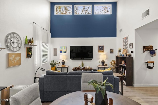 living room featuring a healthy amount of sunlight, light hardwood / wood-style floors, and a high ceiling