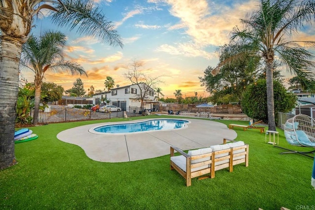 pool at dusk featuring a yard and a patio