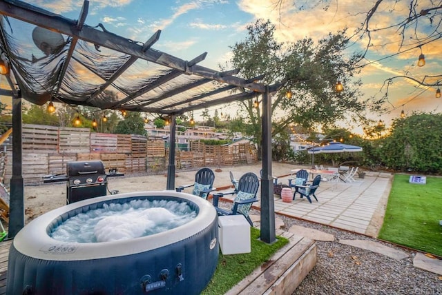 patio terrace at dusk with grilling area, a hot tub, and a pergola