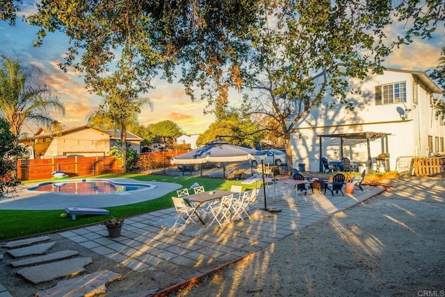 pool at dusk featuring a yard and a patio area