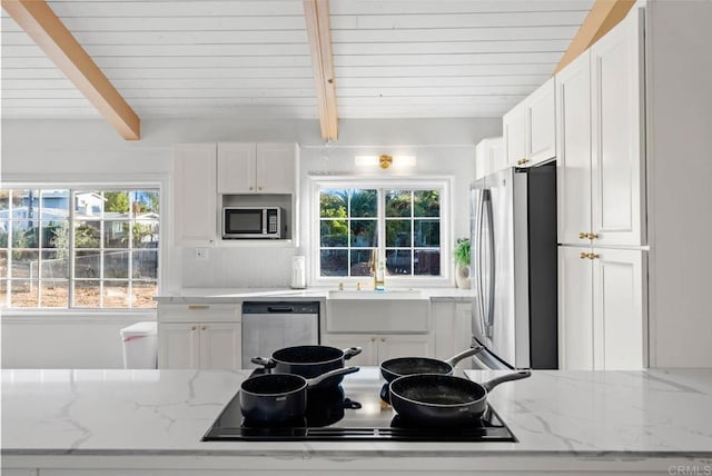 kitchen featuring sink, white cabinetry, stainless steel appliances, beam ceiling, and light stone countertops