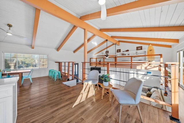 living area with ceiling fan, wood-type flooring, and vaulted ceiling with beams