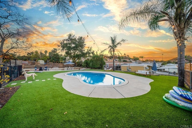 pool at dusk with a lawn and a patio