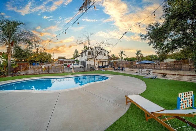 pool at dusk featuring a yard and a patio area