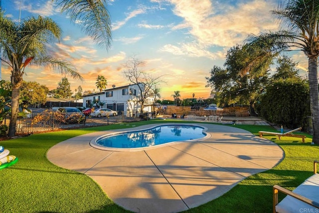 pool at dusk with a yard and a patio