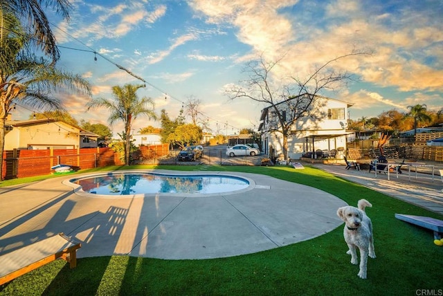 pool at dusk featuring a yard and a patio area