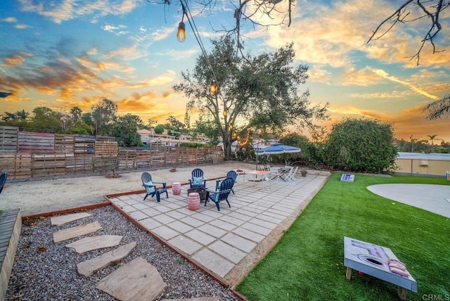 patio terrace at dusk featuring a yard