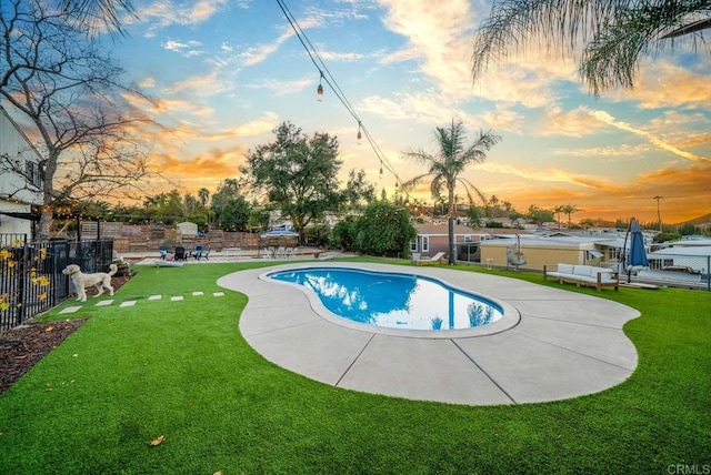 pool at dusk with a patio and a lawn