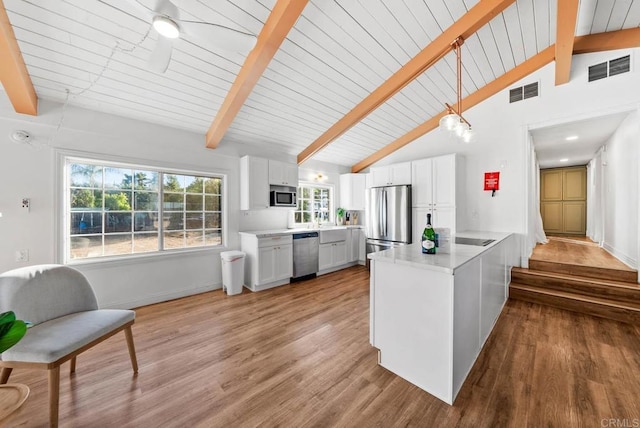 kitchen featuring vaulted ceiling with beams, white cabinets, hanging light fixtures, stainless steel appliances, and light hardwood / wood-style flooring