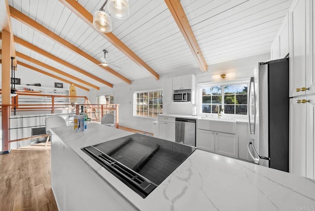 kitchen featuring lofted ceiling with beams, white cabinets, hanging light fixtures, light stone counters, and stainless steel appliances