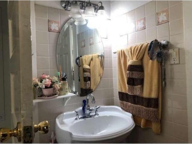 bathroom with tasteful backsplash, sink, and tile walls