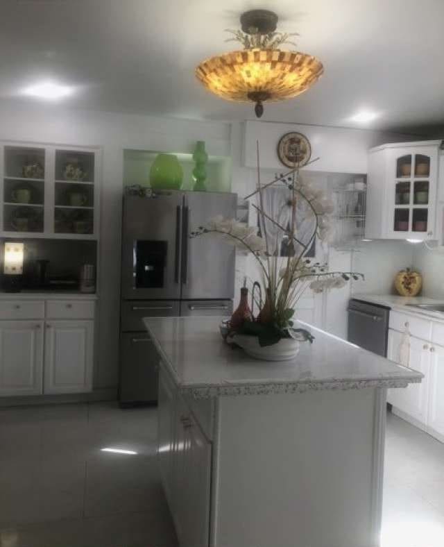 kitchen with white cabinetry, hanging light fixtures, a kitchen island, and appliances with stainless steel finishes