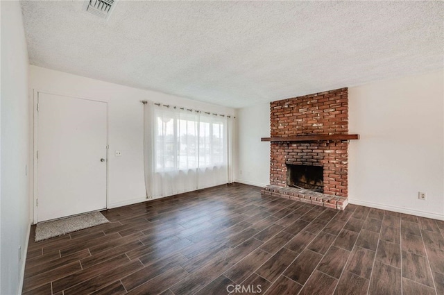 unfurnished living room with a textured ceiling, a fireplace, visible vents, baseboards, and wood tiled floor