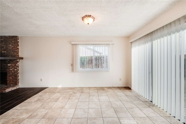 unfurnished living room with a textured ceiling, a fireplace, and light tile patterned flooring