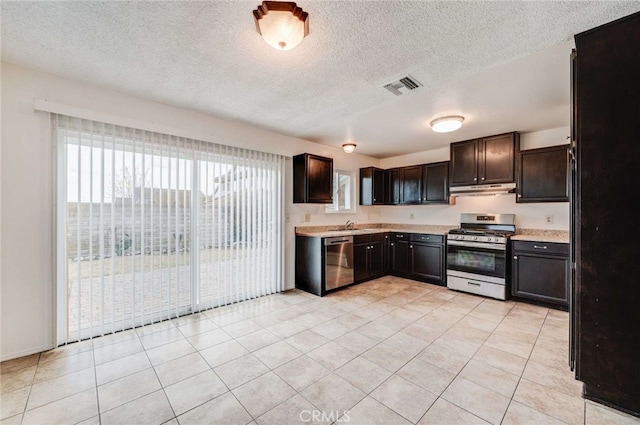 kitchen with dark brown cabinetry, under cabinet range hood, stainless steel appliances, visible vents, and light countertops