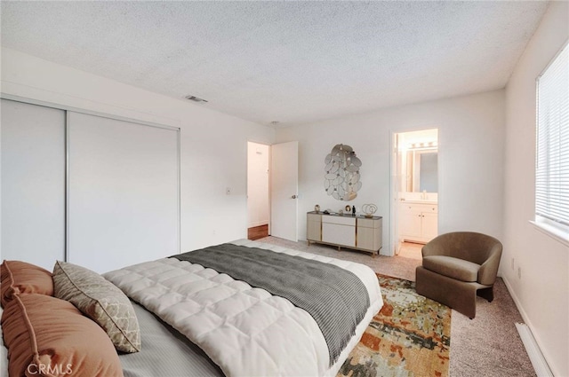 bedroom featuring light carpet, a textured ceiling, visible vents, and a closet