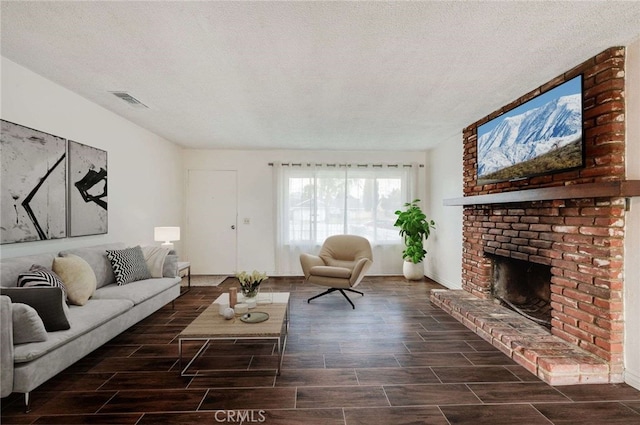 living room featuring wood finish floors, visible vents, a fireplace, and a textured ceiling