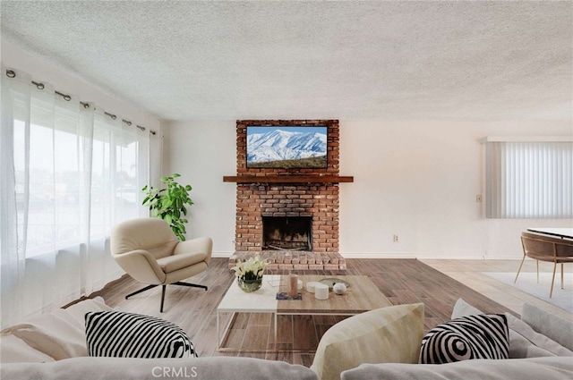 living room featuring light wood-style floors, a fireplace, baseboards, and a textured ceiling