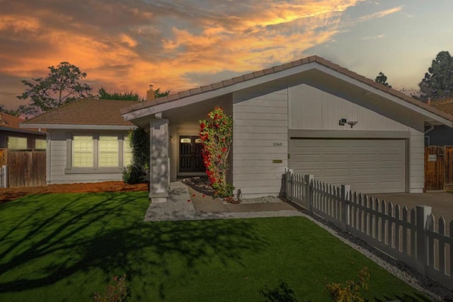 ranch-style house featuring a garage and a yard