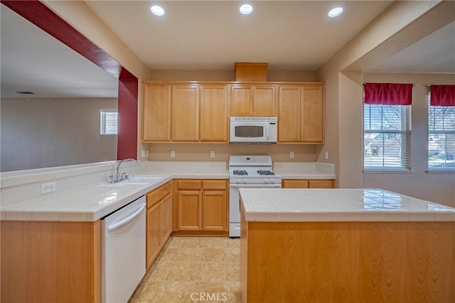 kitchen featuring sink, tile countertops, a center island, kitchen peninsula, and white appliances