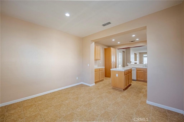 kitchen with a kitchen island, sink, light brown cabinets, and dishwashing machine