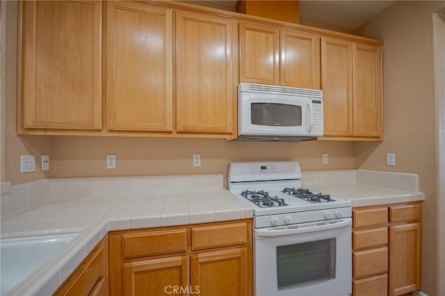 kitchen with light brown cabinets, sink, tile counters, and white appliances