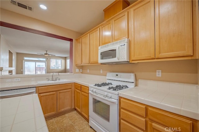 kitchen with sink, white appliances, tile countertops, and ceiling fan