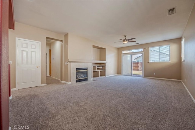 unfurnished living room with a fireplace, ceiling fan, and carpet