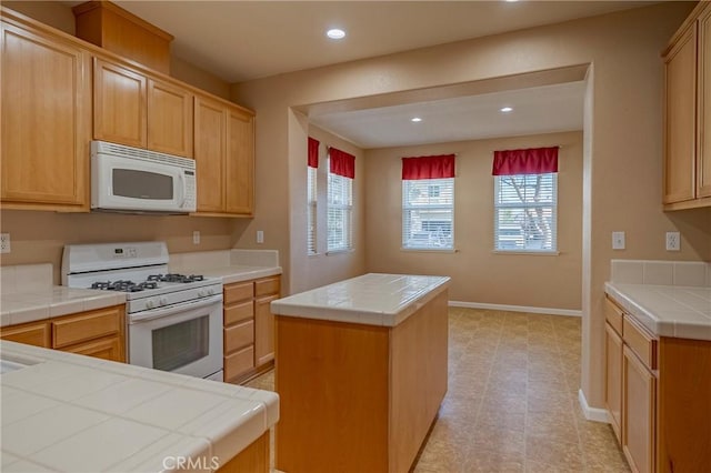 kitchen featuring white appliances, tile counters, and a center island