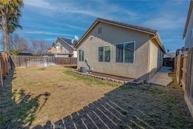 back of property with central AC and a lawn